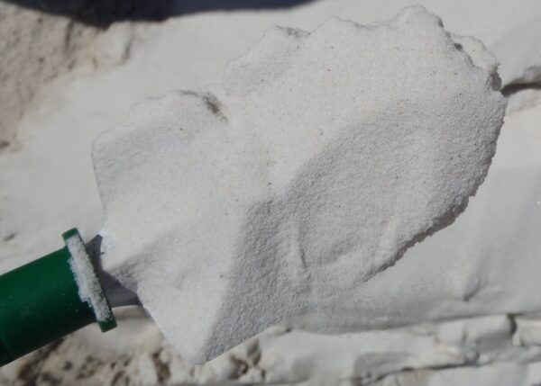 White sand on green shovel