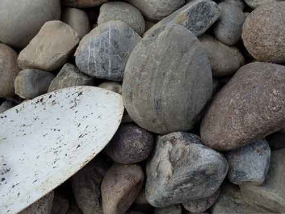 1-3 inch decorative river rock with a shovel