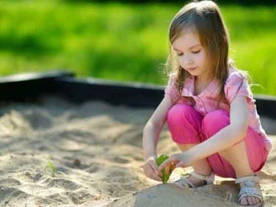 Child playing in a sandbox filled with white sandbox sand