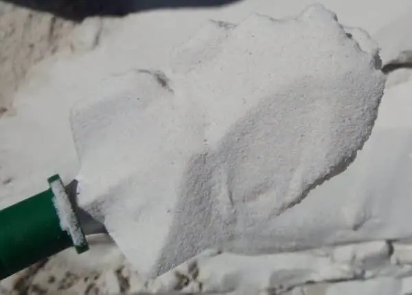White sand on green shovel